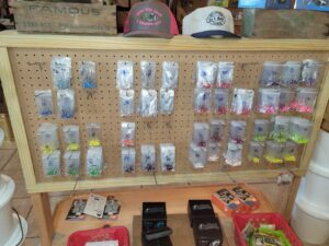 bt 5 A pegboard display with assorted fishing tackle items in plastic bags, hats on top, and boxes on the lower shelf.