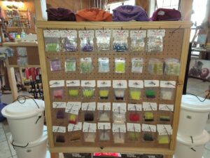 bt 7 A display board with various fishing lures in clear plastic packaging arranged by color and type in a store.